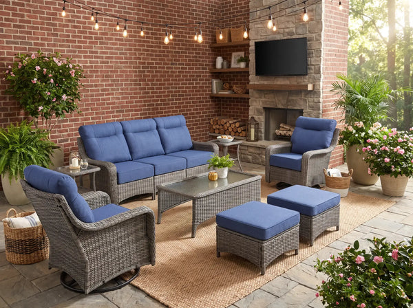 OuterCraft 8-piece all-weather wicker patio furniture set with blue cushions in a brick fireplace courtyard setting.