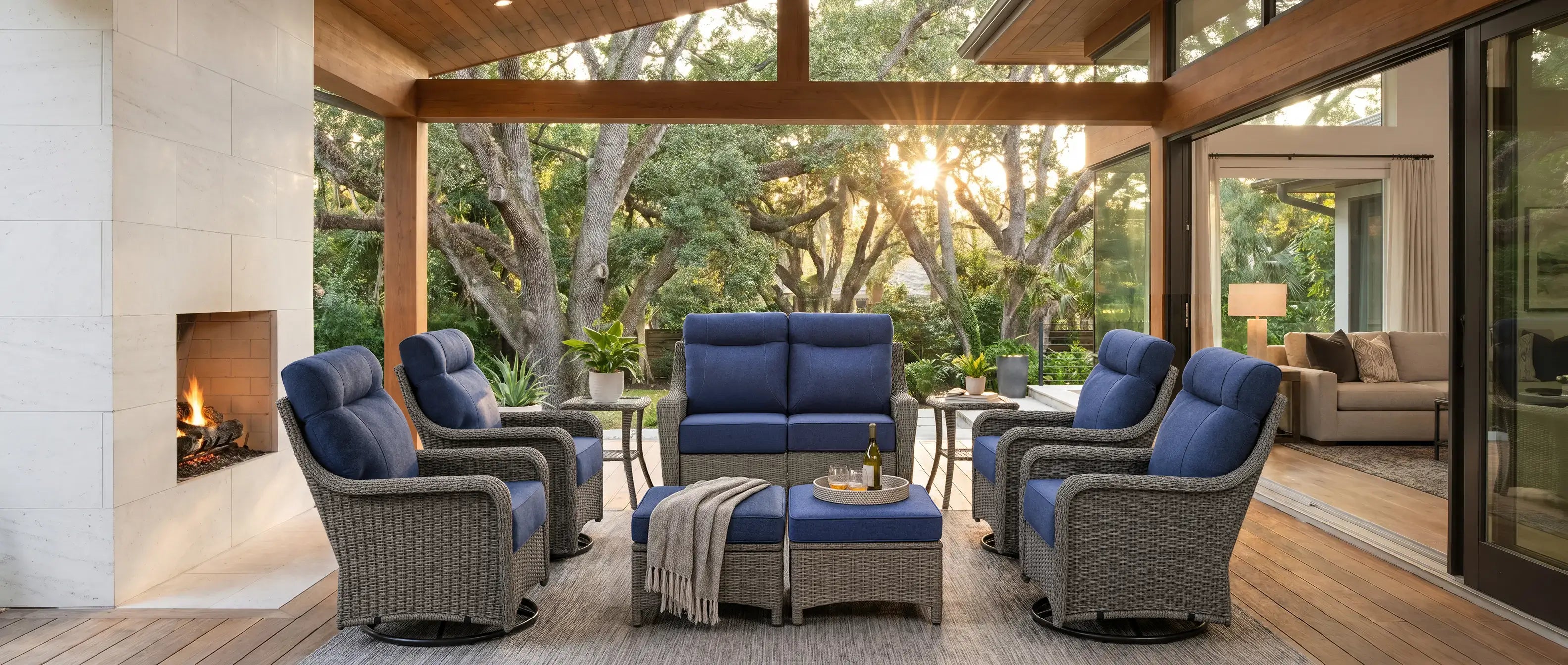OuterCraft 9-piece estate outdoor wicker furniture suite featuring loveseat, 4 swivel rocker chairs, ottomans, and side tables in Blue Olefin cushions in luxury sunroom patio