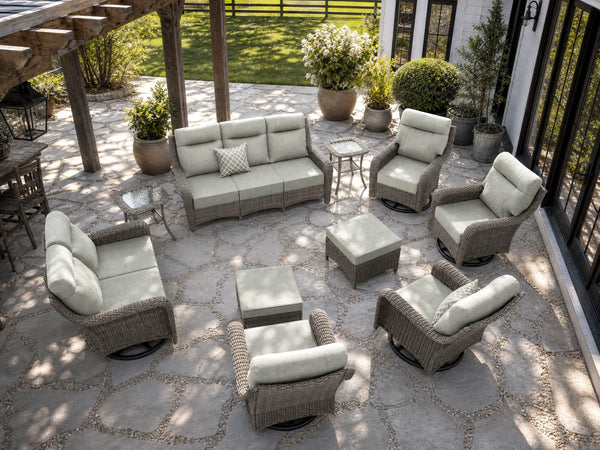 OuterCraft 10-piece dark PE rattan patio set with 3-seater sofa, loveseat, 360-degree swivel rocker chairs, ottomans and side tables with 6-inch thick light gray cushions styled on a grand estate patio