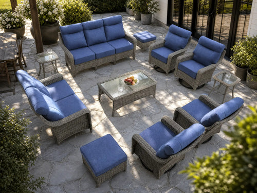 OuterCraft 11-piece dark PE rattan patio set with 3-seater sofa, loveseat, 360-degree swivel rocker chairs, ottomans, coffee table and side tables with 6-inch thick blue cushions styled on a grand estate patio