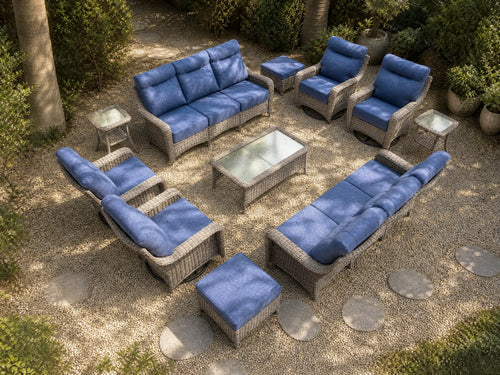 OuterCraft 11-piece dark PE rattan patio set with 3-seater sofas, 360-degree swivel rocker chairs, ottomans, coffee table and side tables with 6-inch thick blue cushions styled on a grand estate patio