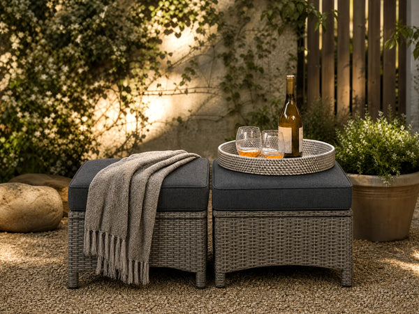 OuterCraft dark PE rattan hand-woven ottomans with thick dark gray cushions styled on a grand estate patio