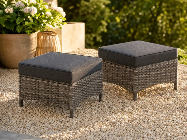 OuterCraft dark PE rattan hand-woven ottomans with thick dark gray cushions styled on a grand estate patio