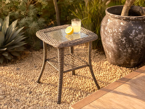 OuterCraft 2-tier dark PE wicker side table with tempered glass top and lower storage shelf styled on gravel patio