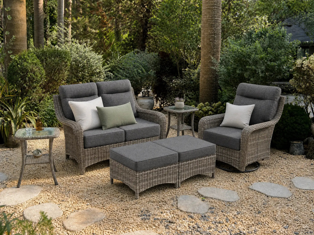 OuterCraft 6-piece dark PE rattan patio set with loveseat, 360-degree swivel rocker chairs, ottomans and side table set with 6-inch thick dark gray cushions styled on a grand estate patio