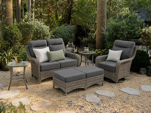 OuterCraft 6-piece dark PE rattan patio set with loveseat, 360-degree swivel rocker chairs, ottomans and side table set with 6-inch thick dark gray cushions styled on a grand estate patio