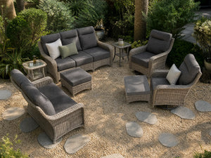 OuterCraft 8-piece dark PE rattan patio set with 3-seater sofa, loveseat with 360-degree swivel rocker chairs, ottomans and side tables set with 6-inch thick dark gray cushions styled on a grand estate patio