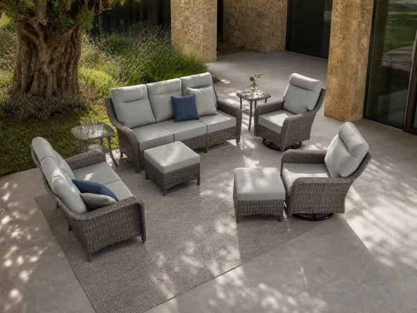 OuterCraft 8-piece dark PE rattan patio set with 3-seater sofa, loveseat with 360-degree swivel rocker chairs, ottomans and side tables set with 6-inch thick light gray cushions styled on a grand estate patio