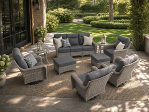 OuterCraft 9-piece dark PE rattan patio furniture set with 3-seater sofa, swivel rocker chairs, ottomans, side tables and dark gray cushions styled on a grand estate patio