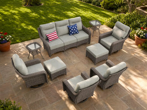 OuterCraft 9-piece dark PE rattan patio furniture set with 3-seater sofa, swivel rocker chairs, ottomans, side tables and light gray cushions styled on a grand estate patio
