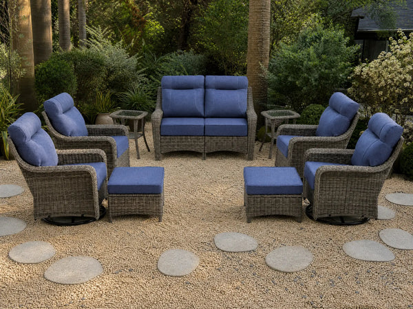 OuterCraft 9-piece dark PE rattan patio set with loveseat, 360-degree swivel rocker chairs, ottomans and side table set with 6-inch thick blue cushions styled on a grand estate patio