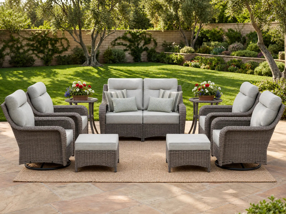 OuterCraft 9-piece dark PE rattan patio set with loveseat, 360-degree swivel rocker chairs, ottomans and side table set with 6-inch thick light gray cushions styled on a grand estate patio