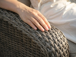 Close-up of hand resting on OuterCraft dark gray hand-woven all-weather PE wicker sofa armrest showing smooth texture