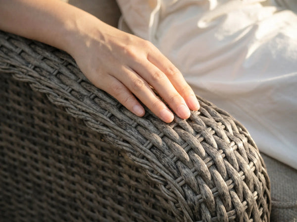 Close-up of hand resting on OuterCraft dark gray hand-woven all-weather PE wicker sofa armrest showing smooth texture
