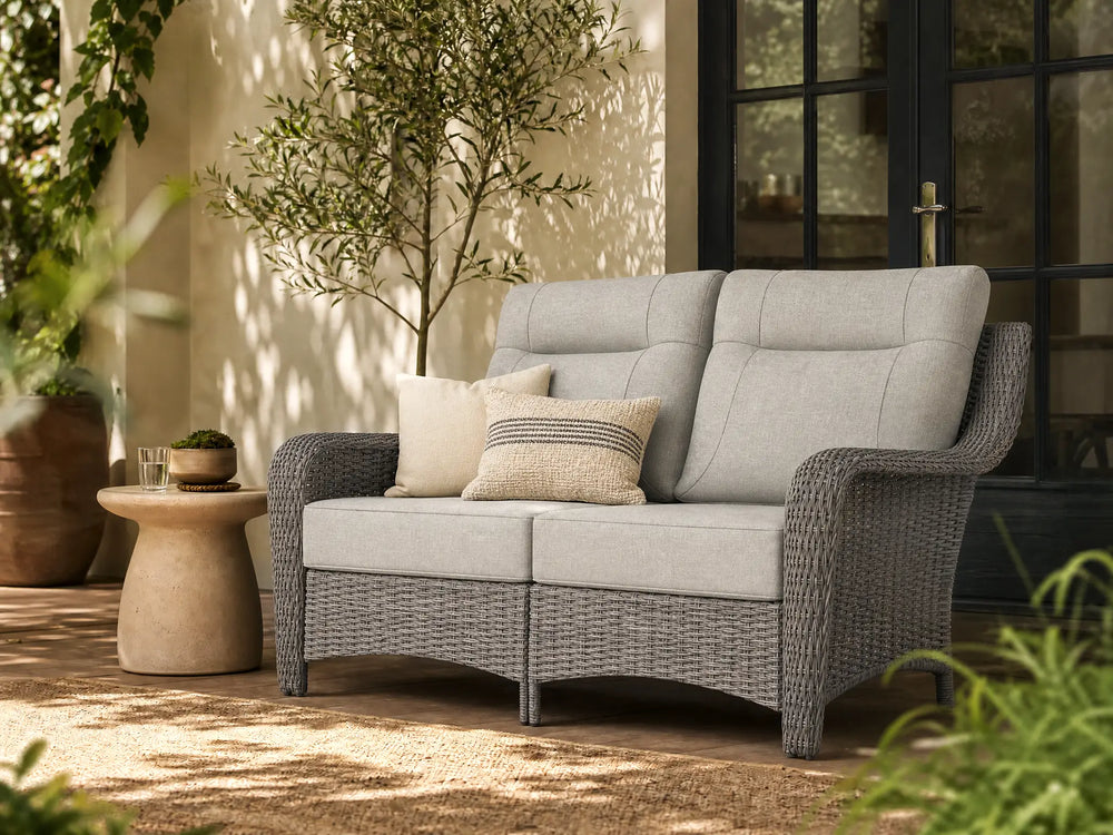 OuterCraft all-weather dark PE rattan loveseat and 6-inch thick light gray cushions styled on a grand estate patio