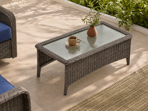 OuterCraft dark PE wicker rectangle outdoor coffee table with tempered glass top styled on sunlit patio