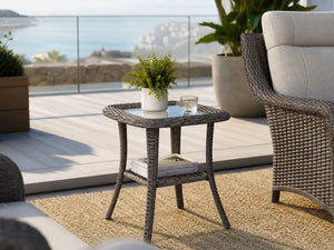OuterCraft all-weather wicker patio side table featuring a premium tempered glass top and a convenient lower storage shelf, perfectly styled on a sunlit coastal balcony alongside our premium lounge seating.